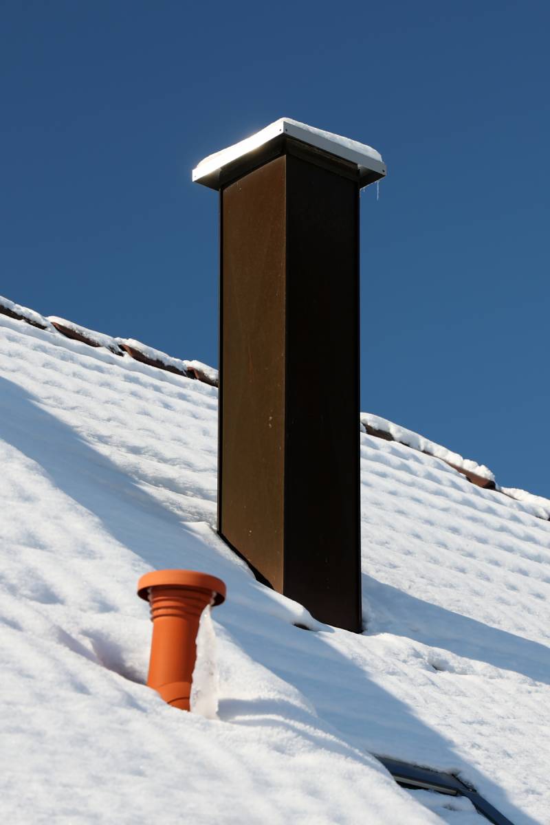 A beautiful view of a roof with a chimney covered with snow in winter