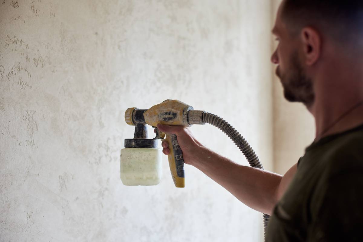 Close-up of man hands hold the tool the paint spray. House remodel.