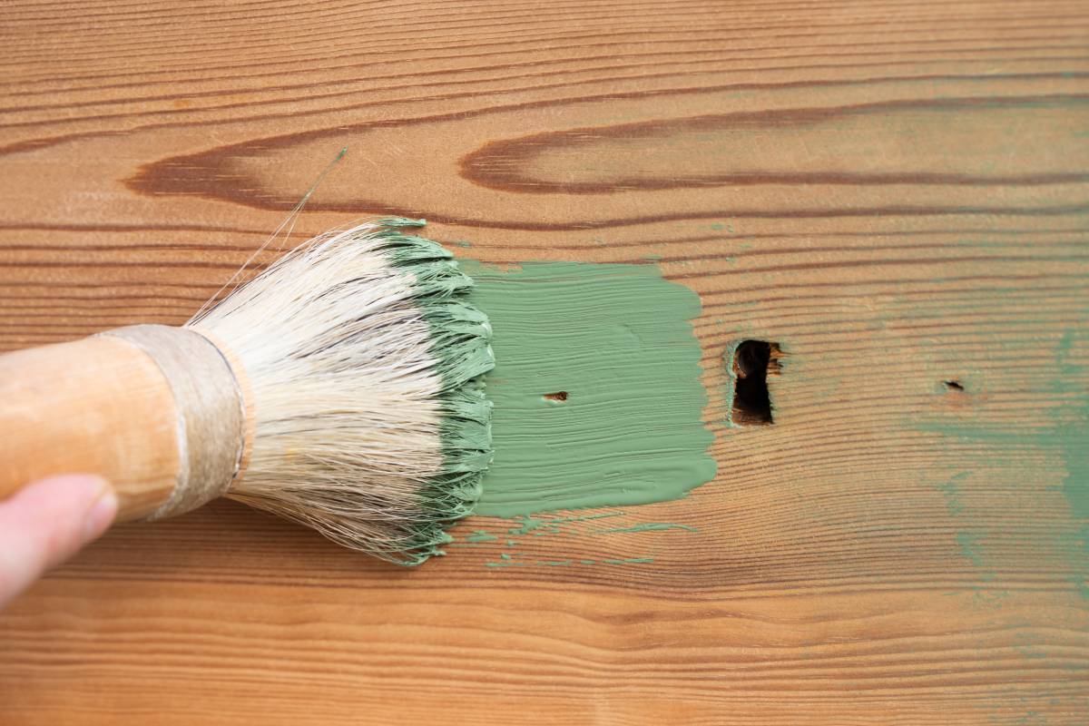 Man painting a wooden furniture outdoors, an eco-friendly re-use business.