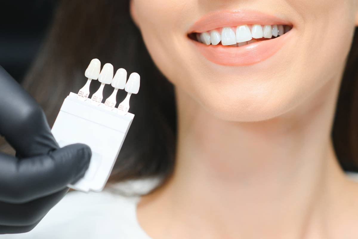 Dentist checking and selecting color of young woman's teeth