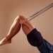 Handsome pilates male instructor performing stretching balance fitness exercise on small barrel equipment, at the pilates studio modern onterior indoor.