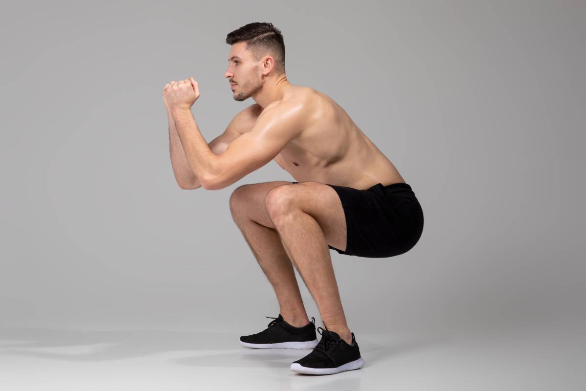 Man Performing Squat Exercise on Grey Background