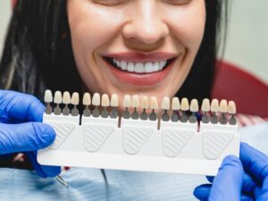 Whitening concept. Dental care, implants,veneers. Woman with perfect smile choosing teeth tooth tone