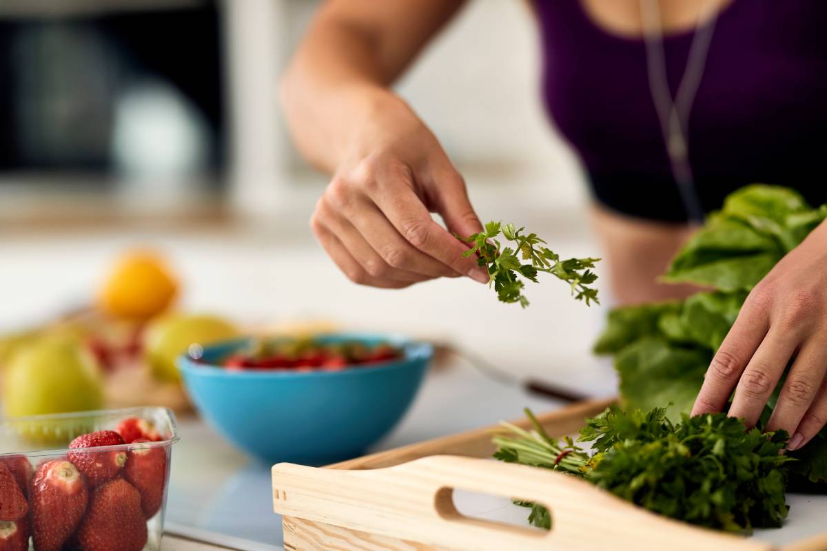 Close-up of woman using parsley while preparing healthy meal.