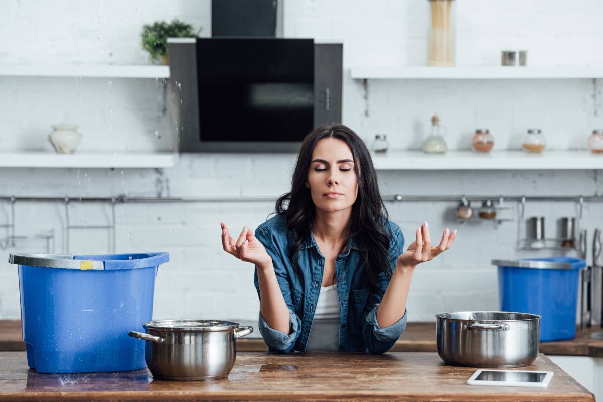 Woman trying to calm down during water damage in kitchen