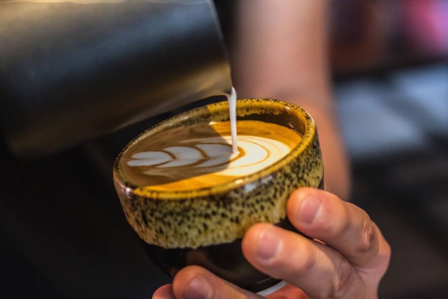 A closeup shot of a male doing a latte art