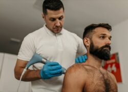 Physiotherapist applying ultrasound therapy treatment on male patient's shoulder