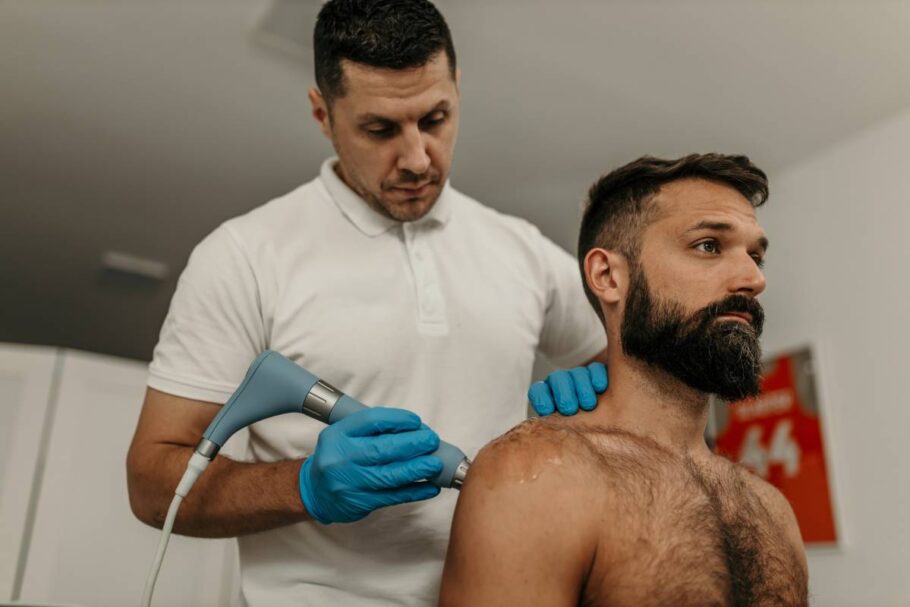 Physiotherapist applying ultrasound therapy treatment on male patient's shoulder